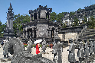 Mausoleum von Khai Dinh in HUe Vietnam, davor eine Frau in rotem Kleid mit Schirm